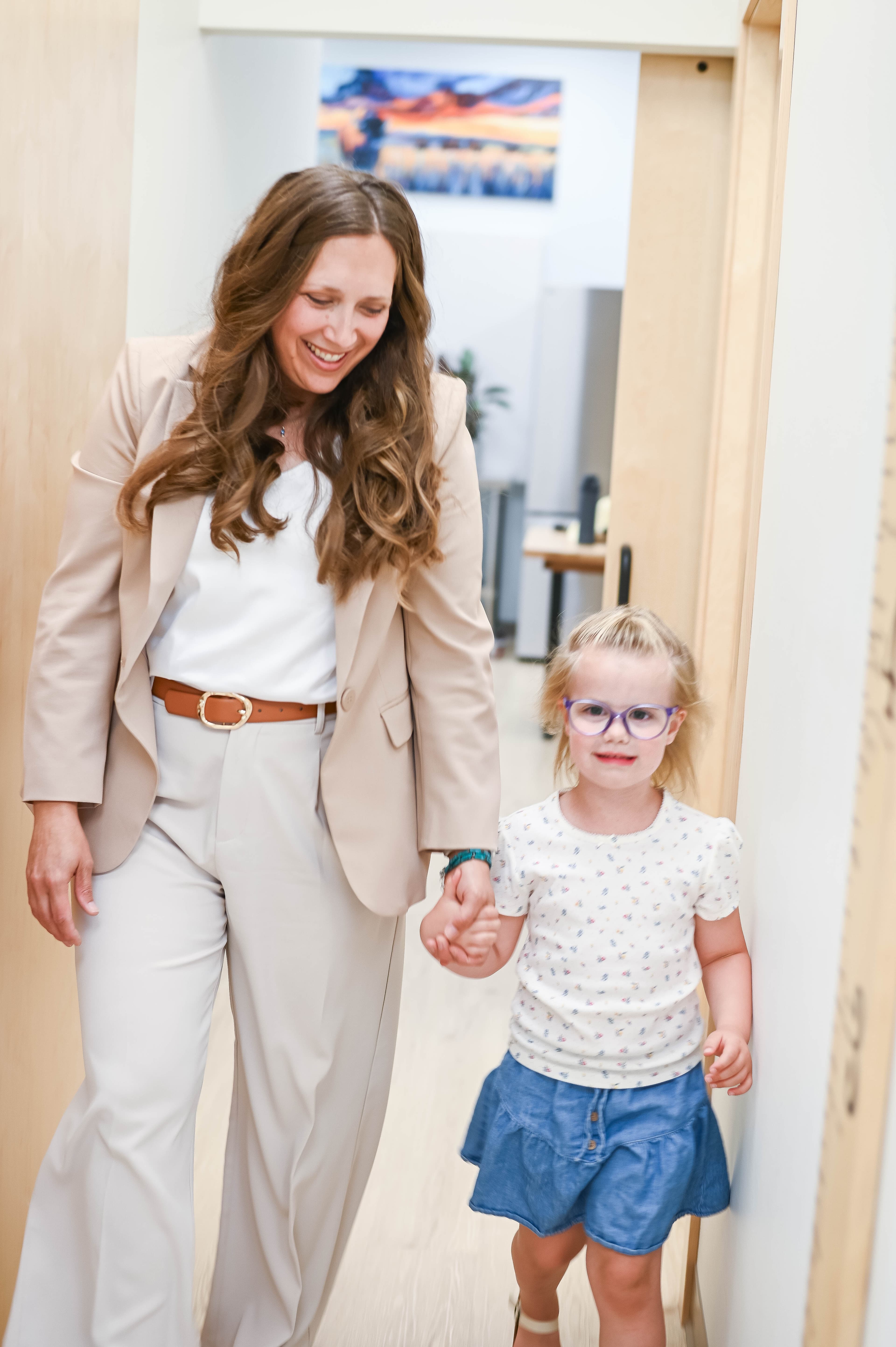 Dr. Michelle walking hand-in-hand with a young patient through the clinic hallway at Dakota Children's Clinic