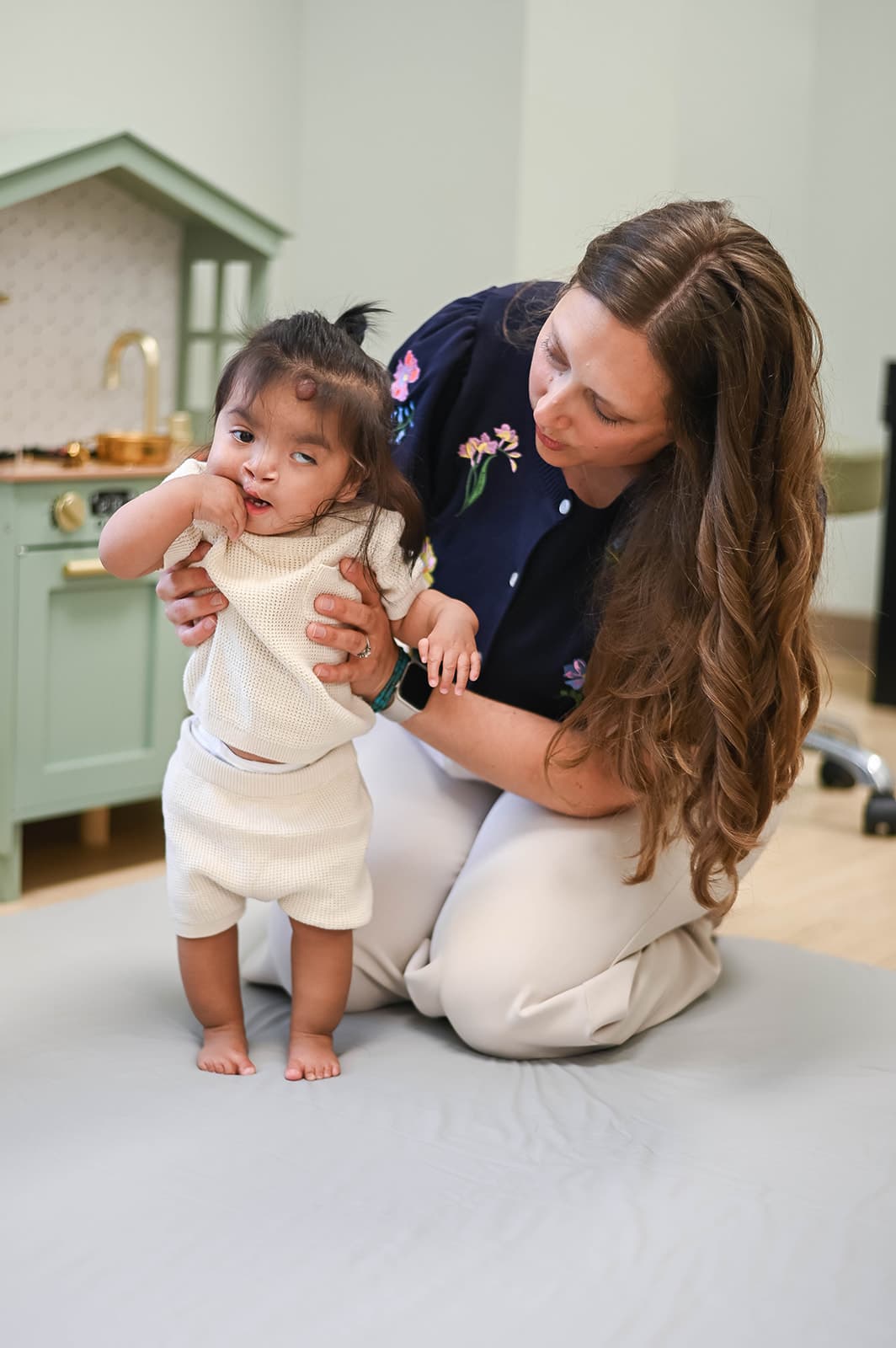 Dr. Michelle kneeling with a toddler on a play mat during an unhurried visit at Dakota Children's Clinic